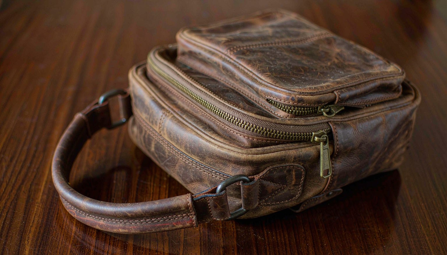 Close-up of a vintage crazy horse leather sling bag showing the natural pull-up grain